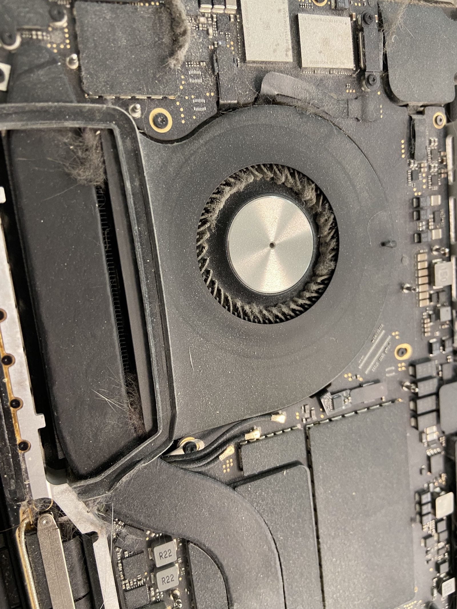 Close-up of a MacBook cooling fan during a fan-cleaning and overheating service