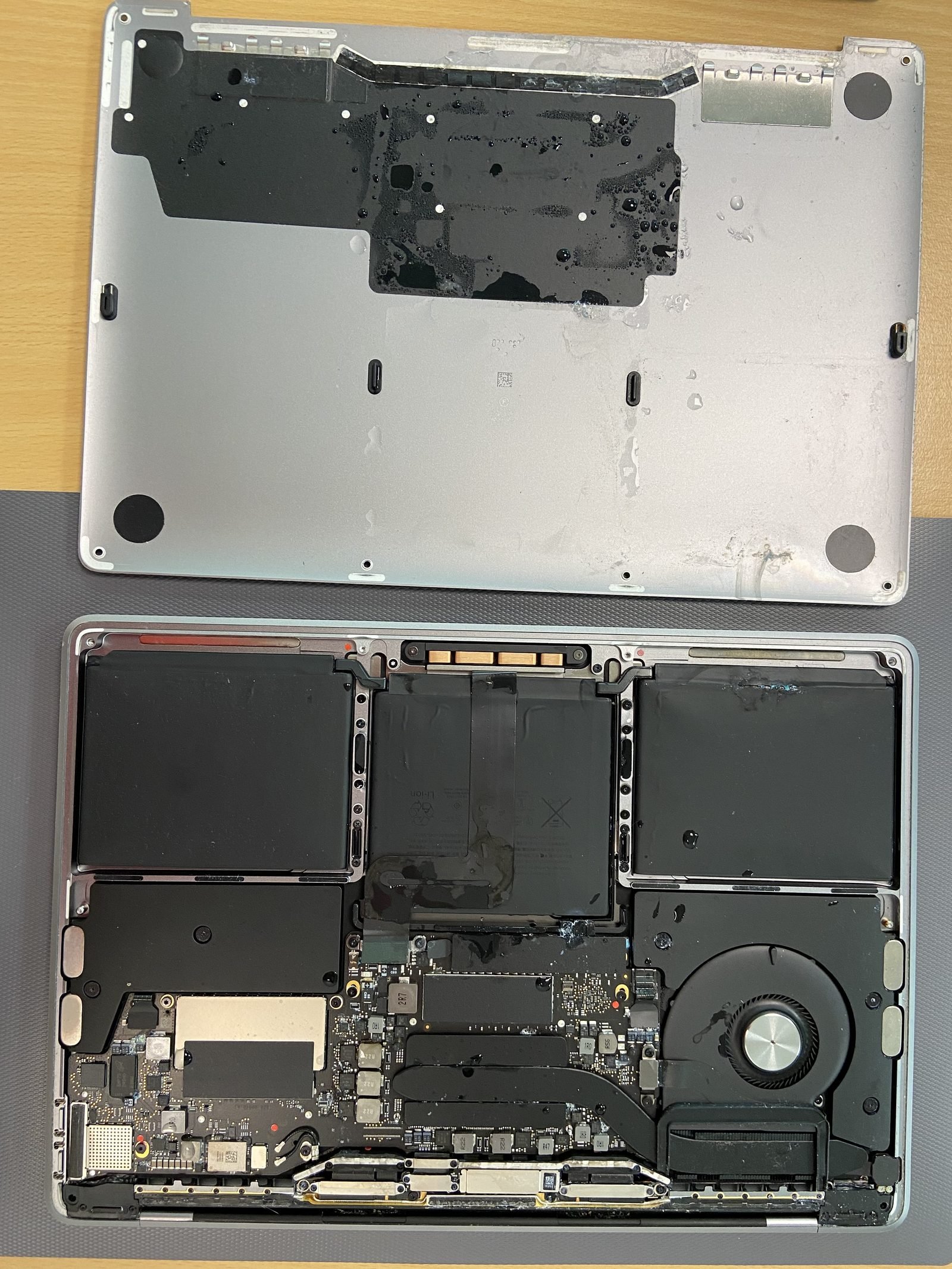 MacBook bottom case removed showing the full internals during a water-damage repair in Dubai