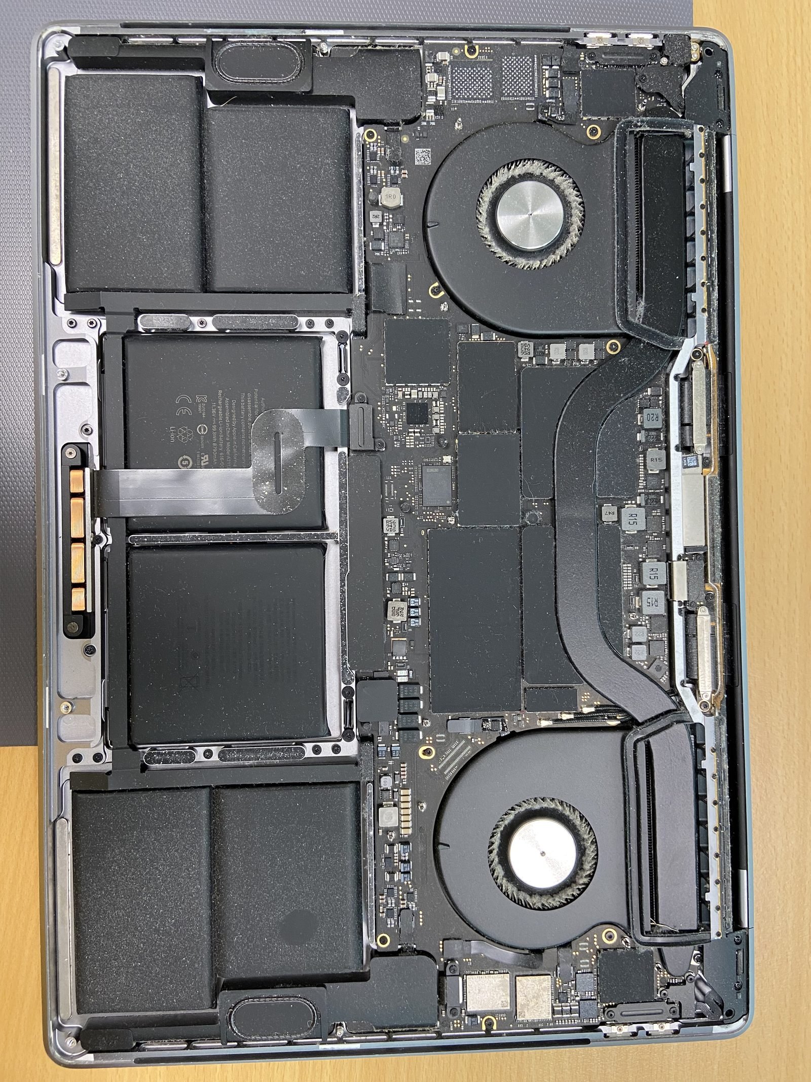 MacBook Pro opened on the bench showing logic board, twin fans and battery during repair in Dubai